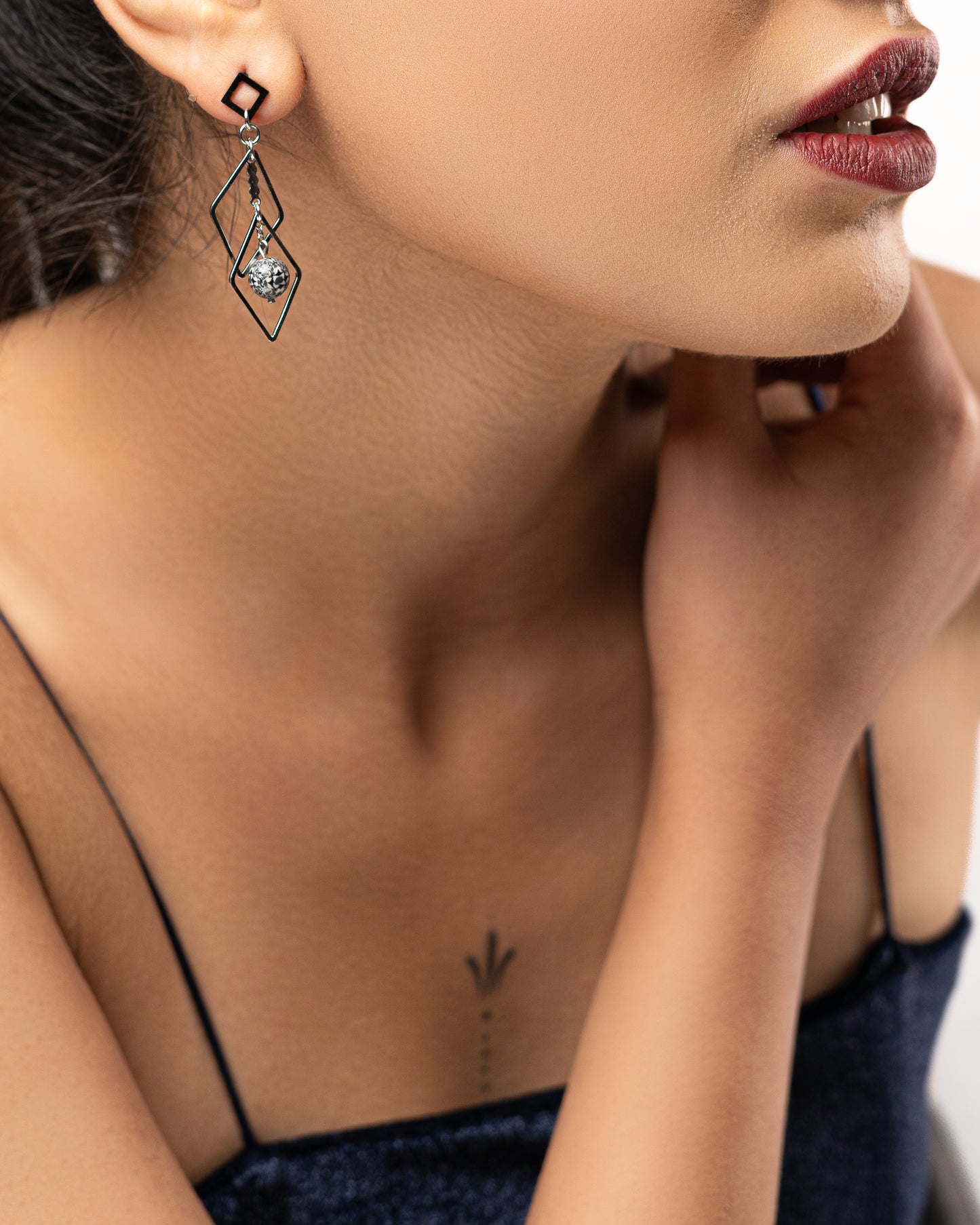 Boucles d'oreilles pendantes géométriques avec des losanges et une perle noir et blanc à motifs suspendue